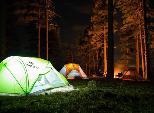 Emplacement camping nocturne Club Brunet tentes dans campement avec feu de bois